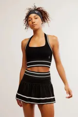 Conjunto deportivo de top y pollera color negro con detalles de líneas blancas en los bordes y la cintura.