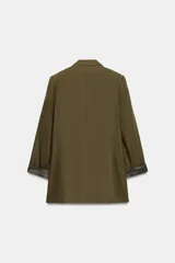 Blazer de lino color verde militar, con cuello solapa, hombreras y manga larga con puño revuelto con detalle a rayas. Cuenta con cierre frontal de un botón y bolsillos delanteros con solapa.