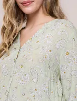 Blusa verde claro con estampado paisley, escote en V con botones frontales y manga larga.