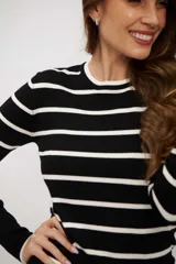 Suéter de punto ajustado, color negro con rayas horizontales blancas. Presenta cuello redondo y mangas largas con puños ajustados.