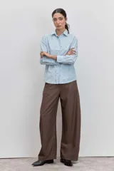 Camisa de algodón color celeste claro, con cuello clásico, cierre frontal de botones y detalle de tachas metálicas plateadas distribuidas por toda la prenda.