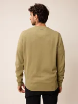 Sweater de punto con cuello en V, manga larga y puños acanalados. Presenta un pequeño logo bordado en el pecho.