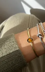 Pulsera rígida dorada con piedra ojo de tigre ovalada engarzada.