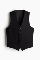 Chaleco de traje negro con cierre frontal de cinco botones y bolsillos ribeteados. Presenta un corte entallado, forro interior y espalda ajustable con trabilla.