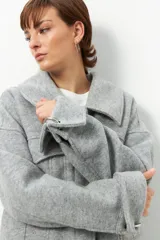 Tapado corto gris de paño, con cuello solapa grande, bolsillos de parche con solapa y mangas largas con puños anchos con presilla y aro metálico.