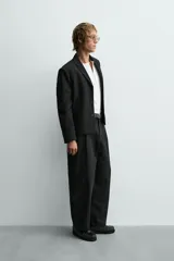 Blazer de corte cropped confeccionado en tejido con viscosa, color negro. Presenta cuello con solapas de muesca, cierre frontal de tres botones, mangas largas con puños abotonados y bolsillos de vivo en la cadera.