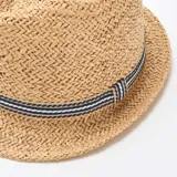 Sombrero de paja estilo Borsalino color beige con cinta decorativa rayada en tonos azul marino y blanco alrededor de la copa.