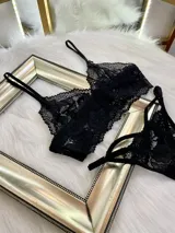 Conjunto de lencería de encaje negro compuesto por un top estilo bralette y una tanga colaless regulable. El top presenta breteles ajustables y diseño sin broches, confeccionado en encaje suave y elastizado.