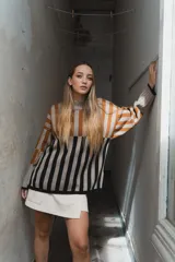 Sweater tejido a rayas horizontales color beige, marrón y negro, de cuello alto y corte holgado.