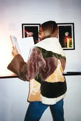 Chaqueta tipo gamulan confeccionada en cuero ovino genuino, con diseño de parches en tonos tierra como beige, marrón, verde oliva y crema. Presenta un corte holgado, cuello amplio y mangas largas con terminación recta.