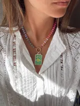 Collar corto de cuentas de colores con dije rectangular verde con diseño de corazón, luna y estrellas.