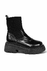 Bota tipo botineta de caña media, confeccionada en una combinación de cuero sintético liso en la parte inferior y tejido de punto acanalado en la caña. Presenta una suela track gruesa y dentada de goma.