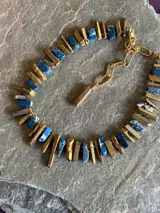 Collar corto de piedras naturales en bruto en tonos dorados y azules, con cadena de eslabones y cierre ajustable metálicos.