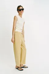 Pantalón de tiro medio color amarillo, con cintura elástica, bolsillos de plastrón en el delantero y pernera holgada que se estrecha hacia el tobillo. Cuenta con cierre frontal de cremallera y botón.