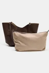 Bolso de hombro tipo maxi shopper, color beige claro, con pespuntes verticales en el cuerpo y doble asa. Incluye un bolso interior con cierre de cremallera metálica y cierre principal imantado.