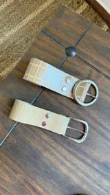 Cinto de ecocuero color beige con hebilla metálica plateada.