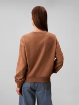 Buzo Calvin Klein de felpa francesa color marrón, con cuello redondo, mangas largas, puños y dobladillo acanalados, y el logo retro de la marca bordado en el pecho.