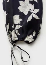 Blusa de manga larga con estampado floral en blanco y negro, cuello redondo y puños elásticos con lazos.