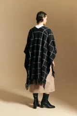 Poncho abierto de tejido de punto con diseño de cuadros grandes en contraste. Presenta un patrón reversible en tonos negro y marrón, con un estilo envolvente y versátil.