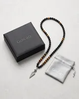 Collar de cuentas esféricas de ónix negro mate y ojo de tigre, con dije central de acero en forma de punta de flecha.