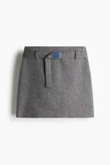 Pollera mini de tiro alto en color gris jaspeado, con diseño estructurado y cinturón extraíble con hebilla metálica rectangular.