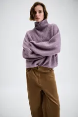 Jersey de punto con cuello alto y cierre frontal de cremallera metálica, de manga larga con puños ajustados y diseño holgado.