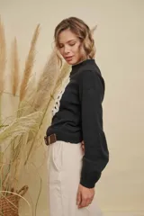 Buzo de punto color negro con cuello redondo, mangas largas y detalle de mandala tejido en color crema en el frente.