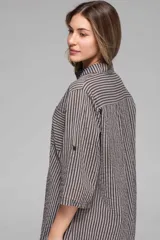 Vestido camisero oversize a rayas verticales en tonos gris y negro, con cuello mao, botonadura frontal, bolsillos frontales a la altura del pecho y mangas 3/4 con opción de arrollar.