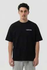 Remera negra de algodón premium con corte relajado. Presenta un diseño gráfico estampado en la espalda que combina tonos violeta y verde ácido, con una ilustración conceptual de un rostro y elementos abstractos.