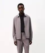 Pantalón slim de sarga color gris, con cintura con pasacintos, cierre de botón y cremallera, bolsillos laterales y bolsillos traseros embutidos.