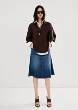 Falda midi evasé de denim azul con diseño de corte trapecio, tiro medio, trabillas y bolsillos.