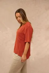 Blusa de manga corta color terracota, con cuello redondo, corte recto holgado y un bolsillo aplicado en el pecho.