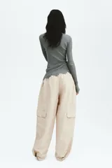 Pantalón cargo de nylon de corte oversized con leve efecto arrugado, cintura elástica fruncida, bolsillos con cierre en el frente y bolsillos con solapa en las piernas.