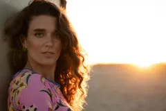 Conjunto de bikini con top corto de manga corta y espalda abierta, y bombacha vedetina. Estampado floral en tonos rosa, amarillo, verde y azul sobre fondo negro.