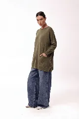 Sweater de tejido de punto con silueta amplia y largo medio. Presenta cuello redondo, mangas largas con puños acanalados, bolsillos frontales y detalle de botones decorativos en el lateral inferior.