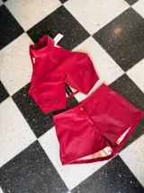 Top corto de cuero sintético color rojo, con cuello alto, cierre en la espalda y abertura en el frente.