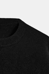 Jersey corto de punto liso, con cuello redondo y manga larga con puños ajustados. Presenta un diseño de corte crop con aberturas laterales en el bajo.