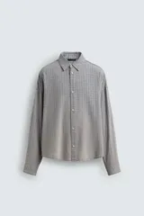 Sobrecamisa de corte relajado confeccionada en tejido de algodón con diseño de cuadros. Presenta cuello solapa, cierre frontal de botones y mangas largas con puños abotonados.