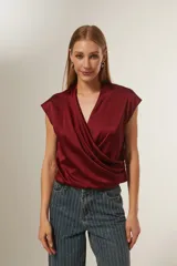 Blusa de satén color bordó, con diseño cruzado tipo sobre, cuello en V y mangas cortas integradas.