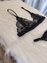 Conjunto de lencería compuesto por un bralette de encaje negro con breteles regulables y una tanga regulable con corte cola less y entrepierna de algodón.