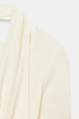 Camiseta de manga larga color crudo con cuello redondo y detalle de top halter superpuesto en el mismo tejido. Presenta un diseño de doble capa con caída drapeada en el frente.