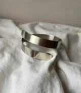 Brazalete dorado de metal con forma de espiral grueso.