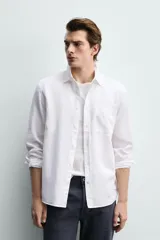 Camisa regular fit de manga larga con diseño a rayas verticales celestes y blancas. Cuenta con cuello abotonado, bolsillo de parche en el pecho y cierre frontal con botones.