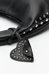 Cartera hobo negra de símil cuero con tachas metálicas plateadas.