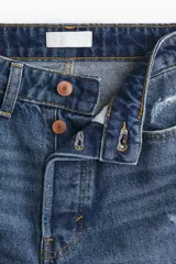 Jean tobillero de cinco bolsillos en denim de algodón, de tiro alto con piernas rectas y detalles de roturas sutiles.