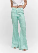 Pantalon de tiro medio con diseño acampanado, confeccionado en mezcla de lino y viscosa con estampado floral en tonos turquesa y blanco. Presenta bolsillos laterales, trabillas para cinturón, costuras decorativas frontales y cierre de cremallera con botón.