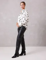 Camisa de satén con estampado de rectángulos negros sobre fondo blanco. Presenta cuello clásico con solapa, cierre frontal con botones metálicos y mangas largas con puños rectos.