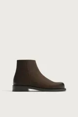Bota de cuero color marrón oscuro con diseño de caña media, horma cuadrada y cierre lateral mediante cremallera. Cuenta con suela a contraste y un ligero tacón.
