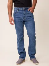 Pantalón de jean corte recto en color azul medio, con cierre de botón y cremallera, y bolsillos laterales y traseros.