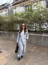 Conjunto de dos piezas de lanilla en color gris melange, compuesto por un buzo oversize de manga larga con aberturas laterales y un pantalón largo de corte recto y holgado.